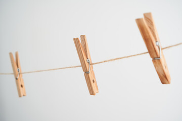 Wooden clothespins on rope on white background.