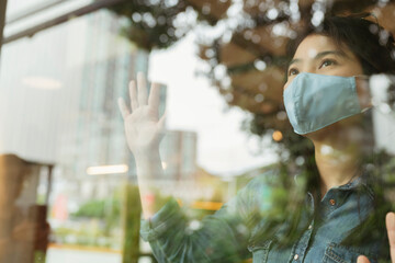asian female casual shirt wear facial mask virus protection new normal lifestyle sit relax next to window glass with reflect of garden outside health and ideas concept
