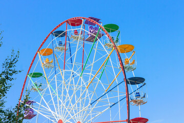 Urban bright Ferris wheel against the blue sky.