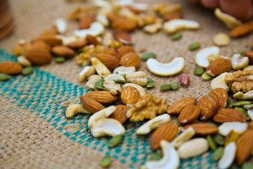 mixed nuts on a brown texture textile slate surface,Whole walnut in wood vintage bowl on a old texture textile background.