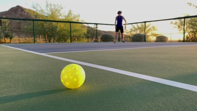 Focus on a Pickleball with Woman Playing in the Background
