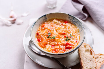 Vegetarian spicy tomato rice soup on grey concrete background. Selective focus