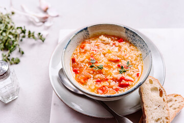 Vegetarian spicy tomato rice soup on grey concrete background. Selective focus