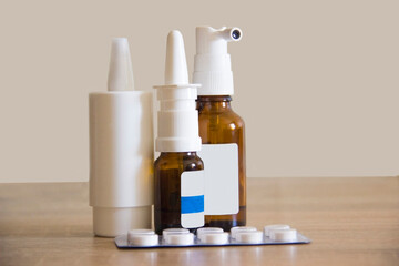 Tablets for sick people are in packaging on the table. Drops for the treatment of rhinitis are on the table in the office. Drops for working at a computer standing on a wooden table.