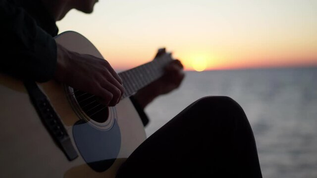 Playing guitar at sunrise, seaside