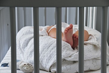 Baby sleeping in the cot bed. Tiny baby toes