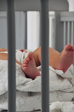 Baby sleeping in the cot bed. Tiny baby toes