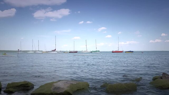 Total picture of lake, clouds on the sky, sailing boats on the water.