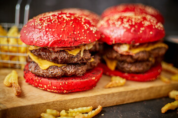 Set of four homemade giant double becon cheese burgers. Served with french fries on wooden board.