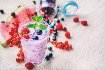 non-alcoholic milkshake smoothies with fresh currant berries, raspberries, watermelon slices and mint leaf on linen textiles