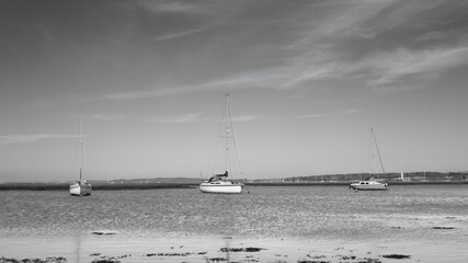 Minimalist landscape composition where three boats rest on the sea at different angles.