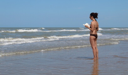 Donna in vacanza al mare in estate che legge un libro - relax e divertimento