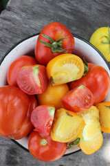 Tomatoes red and yellow in a saucer on a wooden table close up