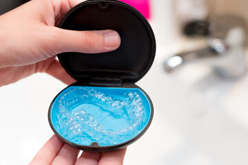 woman's hand holding a case with invisible aligners for dental correction. mobile orthodontic