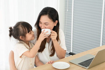 Obraz na płótnie Canvas young asian girl handling tea cup to her asian mother who lying on the bed in bedroom at home. family together and relationship concept