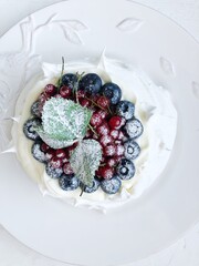 Anna Pavlova dessert with blueberries and red currants