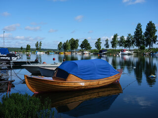 Naklejka na ściany i meble A beautiful wooden boat in a harbour in Sweden. The hull is varnished with the water reflecting. The photograph is shot with a medium format camera