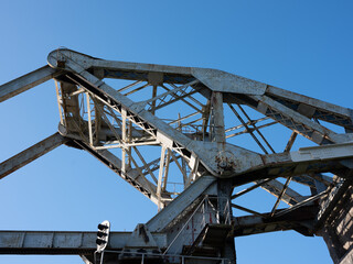 Photograph of a crane structure shot against a blue sky. It is dawn and the sun illuminates the side of the structure. The photograph is shot with a medium format camera.