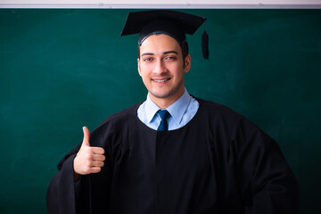 Young male graduate in front of board