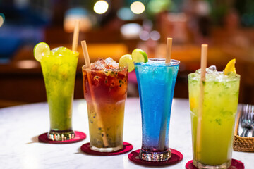 Multiple colourful fresh cocktail drink with ecofriendly wooden straw in a restaurant in Bali