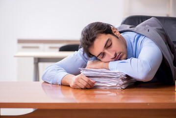 Fototapeta premium Young male employee sleeping in the office