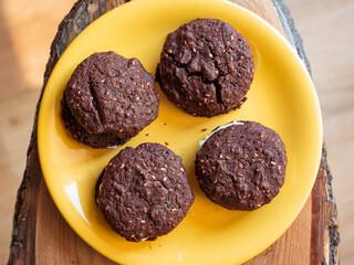 Chocolate and sesame yo-yo's chocolate biscuits or cookies on a yellow plate on a wooden table. Lovely yellow and brown colours