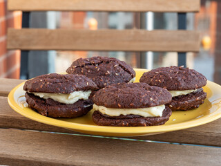 Chocolate and sesame yo-yo's chocolate biscuits or cookies on a yellow plate outdoors