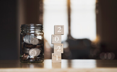 English pound string coin and pennies nickels in jar with 2021 on wooden stack with blurry background,Financial planing for 2021 New Year resolution for saving money for future in business or life