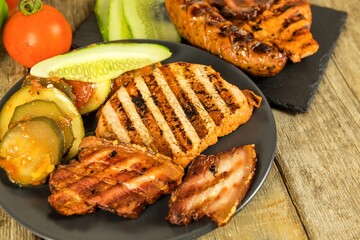 Grilled sausage and pork chops. Wooden background. Grilled meat. Unhealthy fatty food.