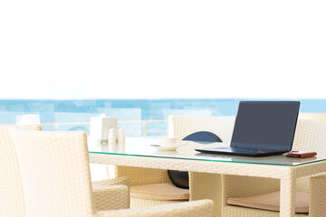 Workplace in a cafe with a sea view. Man working on a laptop in a cafe. Copy space. Mock up.