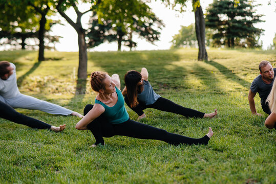 A group of people do yoga in the Park at sunset. Healthy lifestyle, meditation and Wellness