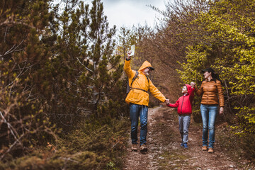 Happy family walking with backpacks in woods and having fun.