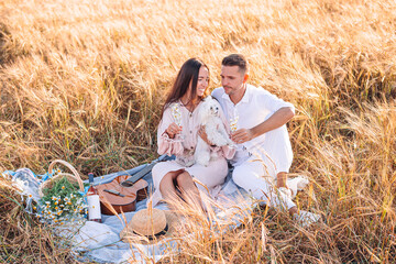 Happy young family on picnic in yellow wheat field
