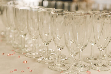 A line empty glasses of hampagne during on the party white table. Celebration concept for wedding day.