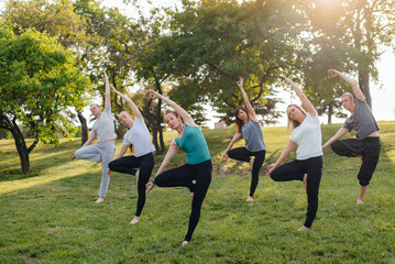 A group of people do yoga in the Park at sunset. Healthy lifestyle, meditation and Wellness