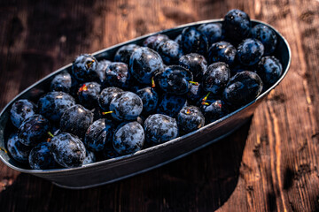 plum in a small metal bathtub on the wooden table in the garden
