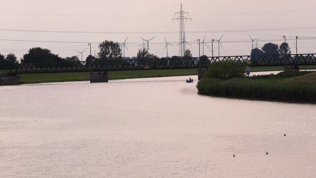 Landschaft an der Leda in der Stadt Leer in Ostfriesland mit Boot in der Ferne, das hinter einer Flusskurve verschwindet