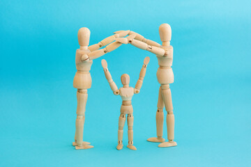 Wooden mannequins mom and dad make figure with hands arms over heads child. Concept - insurance, home, family.