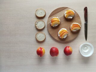  sandwiches with cream cheese, fresh nectarines slices on a serving wooden plank and ingredients. 