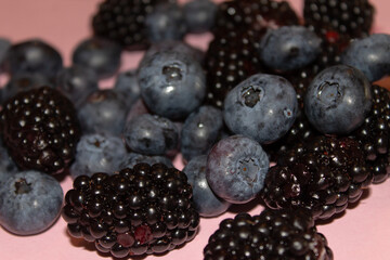 Blueberries and blackberries on a pink background