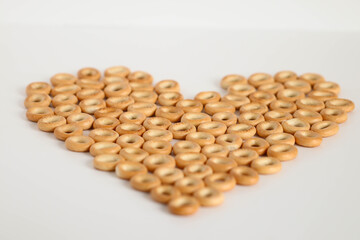 Small wheat bagels in the shape of a heart on a white background, traditional Russian food. Macro photography. Valentine's Day