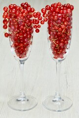 fresh red currant berries pouring out of glassware on the table