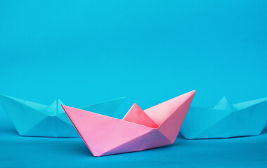Obraz premium blue and pink paper boats abstract vision of man and woman. gender issue, standing out from the crowd, leadership or difference concept. personality struggle for equality