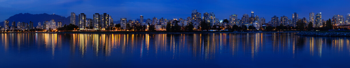 Fototapeta na wymiar Wide Panorama of West End Vancouver skyline at twilight reflected in English Bay