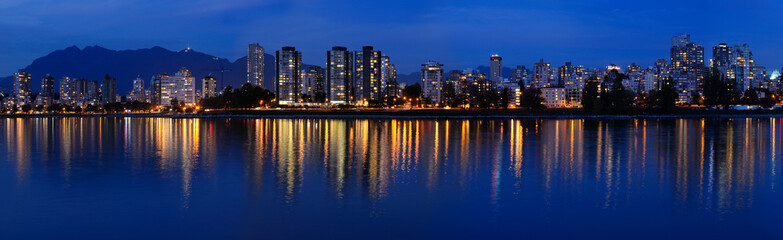 Fototapeta na wymiar Panorama of West End Vancouver skyline at twilight reflected in English Bay from Vanier Park