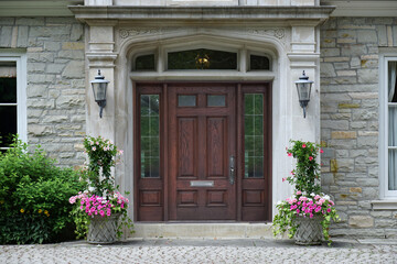 Fototapeta na wymiar Elegant wooden front door with sidelights, with floral decorations, on stone faced house