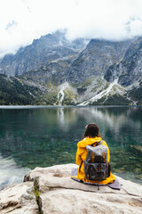 woman backpacker sitting on rock enjoying the view of lake at tatra national park mountains