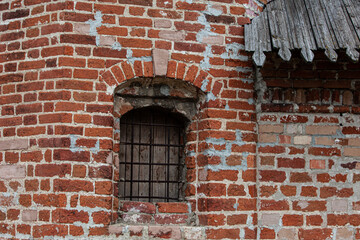 Fototapeta na wymiar Fragment of old brick kremlin wall with window and timber roof