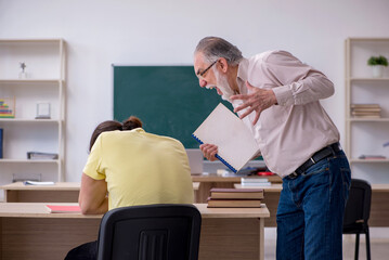Old teacher and young male student in the classroom