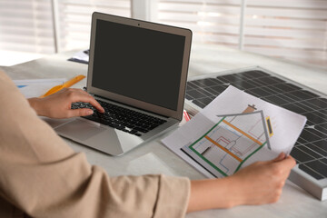 Woman working on house project with solar panels at table in office, closeup